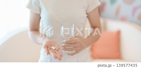 woman hand holding medicine painkiller pill and water glass on the sofa at home, taking for headaches, stomach ache, Diarrhea Pain from food poisoning, Endometriosis, Hysterectomy and Menstrual woman hand holding medicine painkiller pill and water glass on the sofa at home, taking for headaches, stomach ache, Diarrhea Pain from food poisoning, Endometriosis, Hysterectomy and Menstrual 139577435