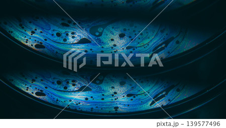 Dye water. Rainbow pollution. Blur blue purple green colorful chemical round oil water liquid leak on abstract dark black background. Dye water. Rainbow pollution. Blur blue purple green colorful chemical round oil water liquid leak on abstract dark black background. 139577496