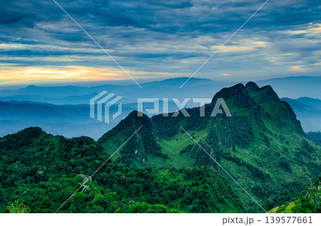 colorful orange sunset behind the foggy sky at the top of the mountain view andd cloudy blue scenery 139577661