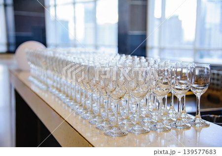 Many empty wine glasses line up waiting to pour some liquor for many invitation guests in the dinner reception celebration party in a lounge in the hotel. 139577683
