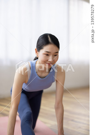 明るい窓辺で髪を結ぶヨガウェアを着た日本人のミドル女性 明るい窓辺で髪を結ぶヨガウェアを着た日本人のミドル女性 139578279