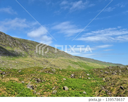 Rocky green hillside under blue sky Rocky green hillside under blue sky 139578637