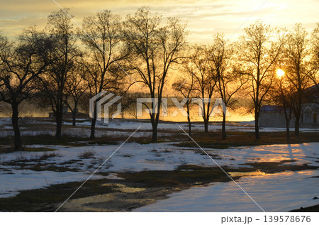 Winter sunset over snowy riverside trees Winter sunset over snowy riverside trees 139578676