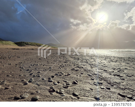 Stormy beach with sunlight breaking through clouds Stormy beach with sunlight breaking through clouds 139578703