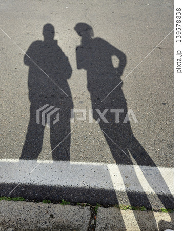 Two Human Shadows on Sunlit Asphalt Road 139578838