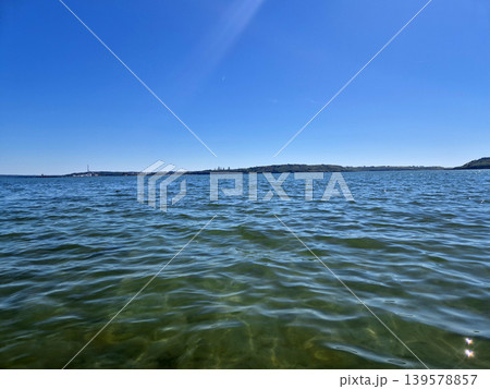 Calm blue sea with distant shoreline and clear sky 139578857