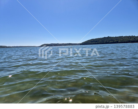 Calm bay water with distant green shoreline 139578883