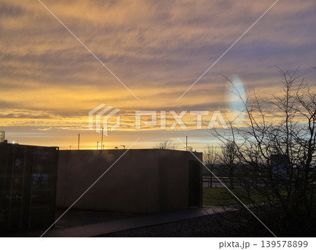 Sunset sky over industrial buildings and bare trees Sunset sky over industrial buildings and bare trees 139578899