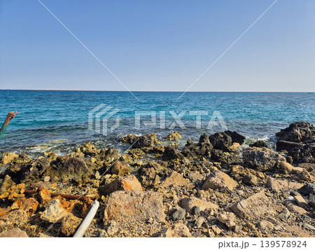 Rocky shoreline with calm blue sea and sky Rocky shoreline with calm blue sea and sky 139578924