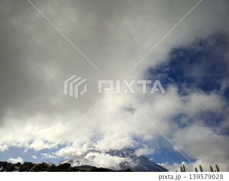 Snowy mountain beneath dramatic cloudy sky Snowy mountain beneath dramatic cloudy sky 139579028