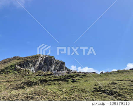 Rocky grassy hillside under clear blue sky Rocky grassy hillside under clear blue sky 139579116