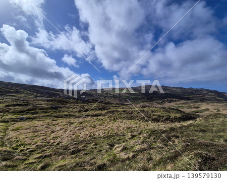 Rugged grassy hillside under dramatic cloudy sky Rugged grassy hillside under dramatic cloudy sky 139579130