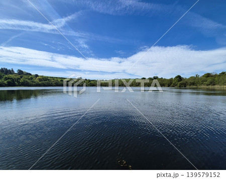 Calm lake under blue sky and clouds Calm lake under blue sky and clouds 139579152