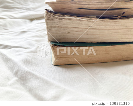 読書・アンティーク・積み上げられた古い本と布の背景・経年変化で日焼けした古本のページ・クローズアップ 読書・アンティーク・積み上げられた古い本と布の背景・経年変化で日焼けした古本のページ・クローズアップ 139581310