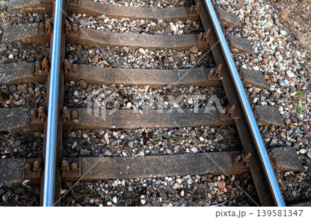Close view of railway ties and gravel along a train track during daytime under clear skies Close view of railway ties and gravel along a train track during daytime under clear skies 139581347