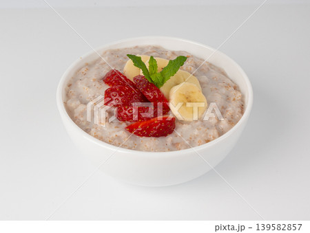 Cooked spelt in bowl isolated. Oatmeal milk porridge with fruits and berries Cooked spelt in bowl isolated. Oatmeal milk porridge with fruits and berries 139582857