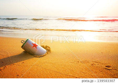 Crumpled beer can on sand beach at sea. Discarded broken can at seashore. Environmental pollution Crumpled beer can on sand beach at sea. Discarded broken can at seashore. Environmental pollution 139583307