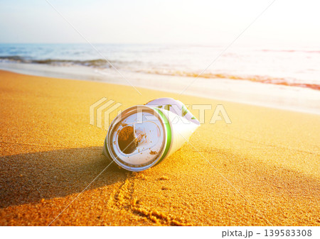 Crumpled beer can on sand beach at sea. Discarded broken can at seashore. Environmental pollution 139583308