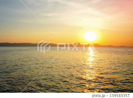 Sunset over ocean, casting warm colors across sky and reflecting on sea water 139583357