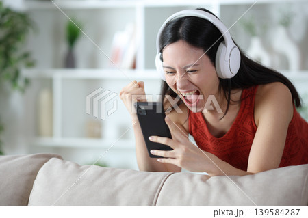Excited asian woman celebrating watching media on phone 139584287