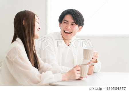 ダイニングテーブルでホットドリンクを飲みながら会話するカップル,夫婦 ダイニングテーブルでホットドリンクを飲みながら会話するカップル,夫婦 139584877
