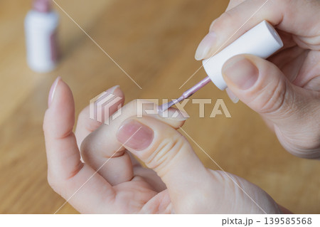 女性が左手の中指にジェルネイル塗っている 139585568