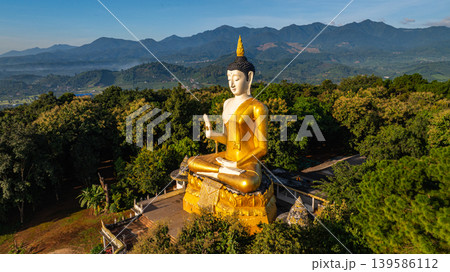 Golden Buddha Statue Overlooking Scenic Mountains 139586112