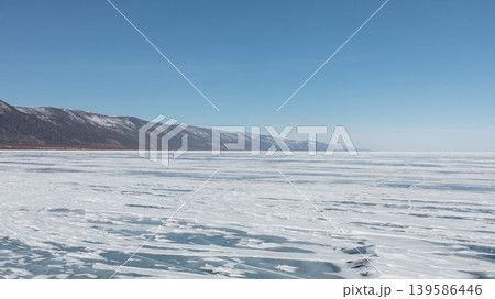 Frozen Lake Baikal winter landscape with ice patterns and mountains, Russia Frozen Lake Baikal winter landscape with ice patterns and mountains, Russia 139586446