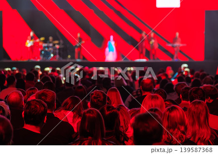 Crowd watching live concert on stage with band and dramatic red lighting Crowd watching live concert on stage with band and dramatic red lighting 139587368