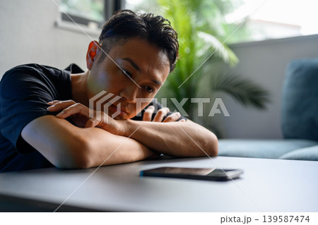 机でスマホを見つめる男性 机でスマホを見つめる男性 139587474
