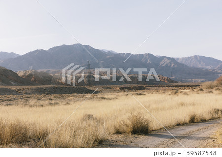 Arid steppe landscape with power lines and mountains in Kyrgyzstan at sunset Arid steppe landscape with power lines and mountains in Kyrgyzstan at sunset 139587538