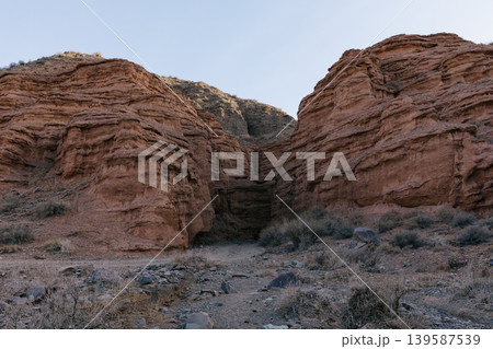 Kok-Moynok Canyon red sandstone cliffs and dry riverbed landscape in Kyrgyzstan Kok-Moynok Canyon red sandstone cliffs and dry riverbed landscape in Kyrgyzstan 139587539