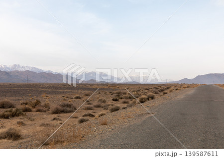 Empty desert highway with distant snowy mountains in Kyrgyzstan, Central Asia Empty desert highway with distant snowy mountains in Kyrgyzstan, Central Asia 139587611