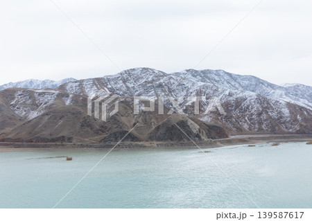 Snowy mountains and turquoise reservoir landscape in Kyrgyzstan, Central Asia Snowy mountains and turquoise reservoir landscape in Kyrgyzstan, Central Asia 139587617