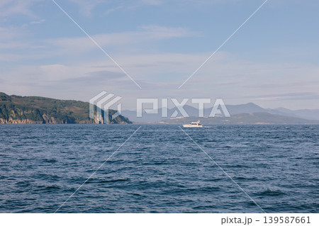 Scenic seascape of Avacha Bay with motor yacht and distant mountains, Kamchatka Scenic seascape of Avacha Bay with motor yacht and distant mountains, Kamchatka 139587661