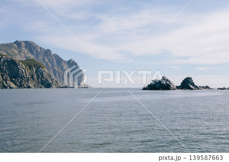 Coastal cliffs and rocky islets in Velyuchinskaya Bay on a calm sea 139587663