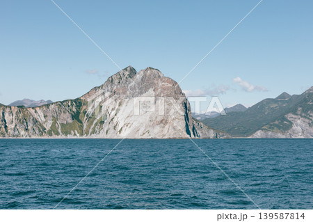 Rocky coastal cliffs and calm sea under clear sky in Kamchatka Peninsula, Russia Rocky coastal cliffs and calm sea under clear sky in Kamchatka Peninsula, Russia 139587814