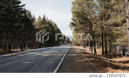 Empty highway through pine forest near Arshan with distant mountains, Buryatia Empty highway through pine forest near Arshan with distant mountains, Buryatia 139587871