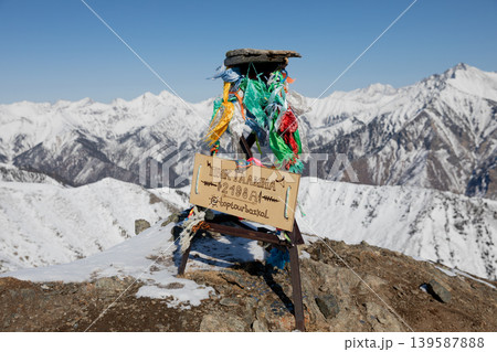 Peak Galina summit sign with prayer ribbons above snowy Sayan Mountains, Arshan Peak Galina summit sign with prayer ribbons above snowy Sayan Mountains, Arshan 139587888