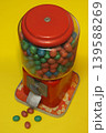 A vintage candy dispenser filled with colorful candies on yellow background 139588269