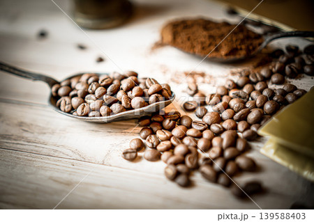 Group of high quality roasted coffee beans, spilled on wooden table. Brown-black shiny whole grains of coffee View from above. 139588403