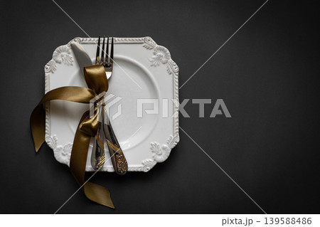 Romantic tabble setting with ribbon, plates, cutlery on black background. Empty plate. Mockup design layout for your text. Love romantic concept. Copy space. Top view. Flat lay. Romantic tabble setting with ribbon, plates, cutlery on black background. Empty plate. Mockup design layout for your text. Love romantic concept. Copy space. Top view. Flat lay. 139588486