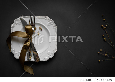 Romantic tabble setting with ribbon, plates, cutlery on black background. Empty plate. Mockup design layout for your text. Love romantic concept. Copy space. Top view. Flat lay. Romantic tabble setting with ribbon, plates, cutlery on black background. Empty plate. Mockup design layout for your text. Love romantic concept. Copy space. Top view. Flat lay. 139588489