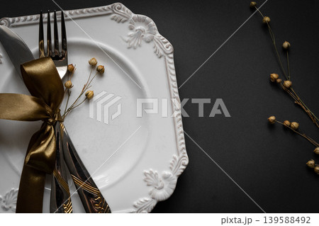 Romantic tabble setting with ribbon, plates, cutlery on black background. Empty plate. Mockup design layout for your text. Love romantic concept. Copy space. Top view. Flat lay. Romantic tabble setting with ribbon, plates, cutlery on black background. Empty plate. Mockup design layout for your text. Love romantic concept. Copy space. Top view. Flat lay. 139588492