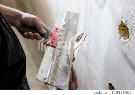 Happy worker man making wall in the room by hand spatula repair Happy worker man making wall in the room by hand spatula repair 139588569