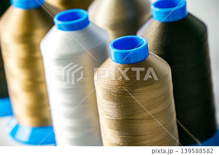 Multicolored spools thread. Spools of multi-colored threads lies on white table, close-up shot photo Multicolored spools thread. Spools of multi-colored threads lies on white table, close-up shot photo 139588582