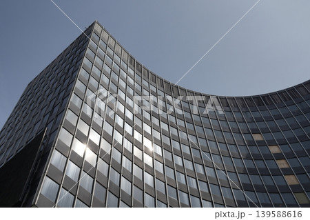 Modern curved building with curved facade and horizontal stripe design against the sky. Modern curved building with curved facade and horizontal stripe design against the sky. 139588616