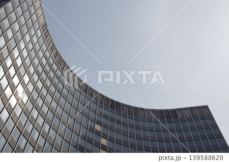 Modern curved building with curved facade and horizontal stripe design against the sky. Modern curved building with curved facade and horizontal stripe design against the sky. 139588620