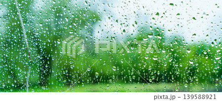 A rainy day window view. Rain drops on window. Condensed rain drop on the car glass window on a rainy day. Dew moisture condensation on wet mirror background. Fresh weather. Water raindrop bg 139588921