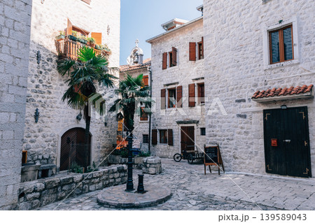 Old stone courtyard with palm trees and historic buildings in Tivat old town 139589043